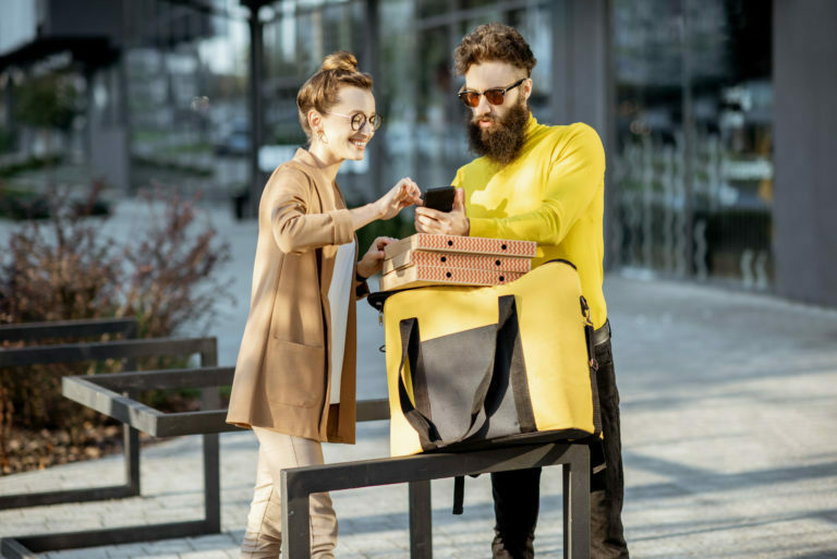 Man delivering pizza to a young woman client