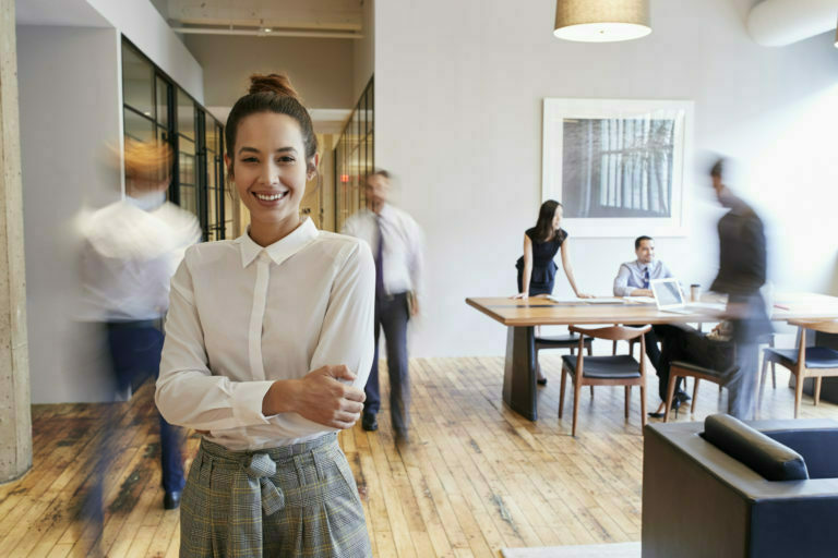 a person smiling in a room with other people in the background