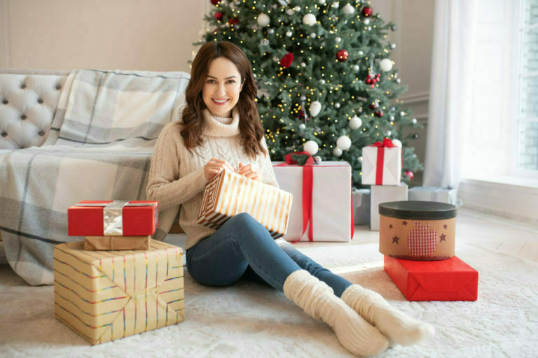 a person sitting on the floor with presents and a christmas tree