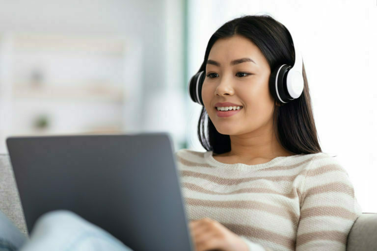 a person wearing headphones and sitting in front of a laptop